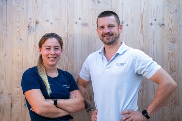 Mann und Frau stehen vor einer Holzwand